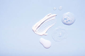 Serum and moisturizing smears cosmetic cream with on colored background. Top view
