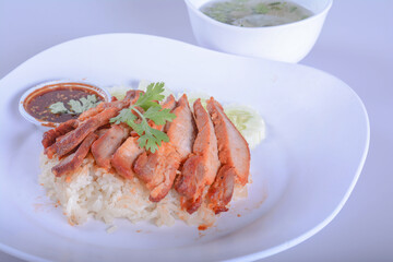 barbecued red pork in sweet sauce with rice and soup on white bowl for Thai food and isolate background 