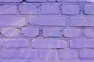 Textured background of a brick street wall painted in a matte purple color.Copyspace.