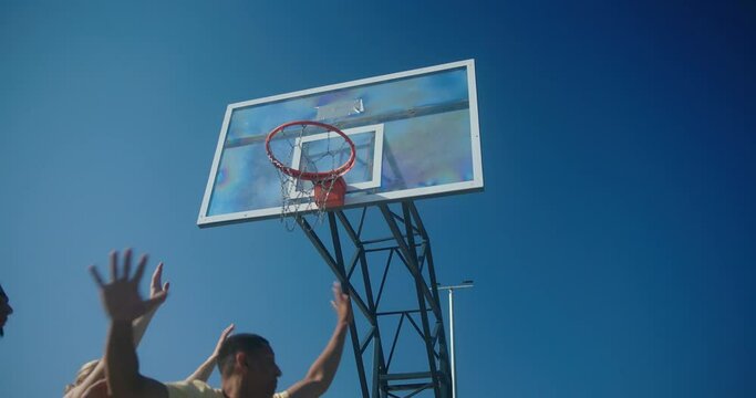 Bearded man wearing blue t-shirt scores ball in hoop closeup