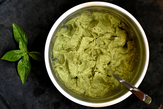 Guacamole dip, mashed avocado in bowl, top view on black background