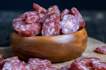 sliced thin sausage with bacon on a wooden dish