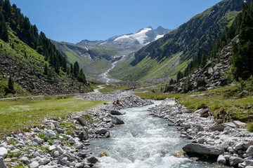 Alpine creek in a mountain valley with a snowy mountain peak in the background