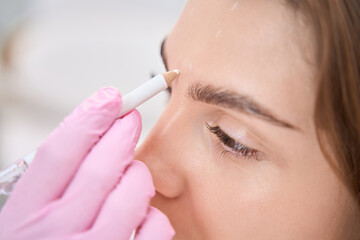 Lady between eyebrows is schematically marked with pencil for procedure