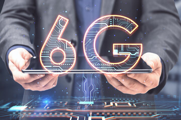 Close up of businessman hand holding tablet with creative 6G hologram on blurry background. Speed, internet and technology, communication concept. Double exposure.