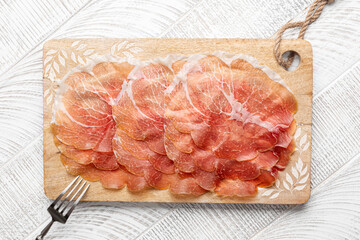 Prosciutto crudo di Parma - italian dry cured ham on a wooden board.