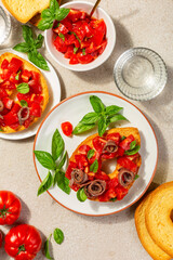 Friselle or frese with anchovy. Twice-baked bagel shaped bread from Puglia, Italy. Ingredients, tomatoes, basil, olive oil. Directly above, vertical image.