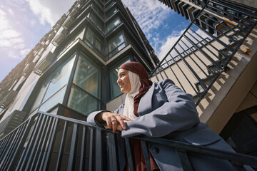 Muslim woman posing on the stairs against the backdrop of tall buildings