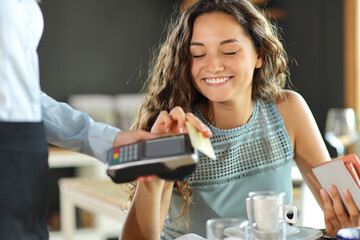 Happy woman paying in a restaurant with credit card