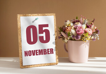 november 5. 5th day of month, calendar date.Bouquet of dead wood in pink mug on desktop.Cork board with calendar sheet on white-beige background. Concept of day of year, time planner, autumn month