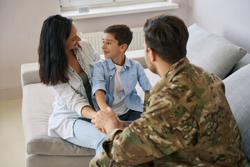 Boy sitting on mother lap during meeting with military father