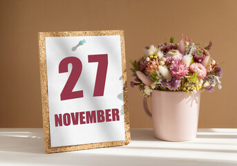 november 27. 27th day of month, calendar date.Bouquet of dead wood in pink mug on desktop.Cork board with calendar sheet on white-beige background. Concept of day of year, time planner, autumn month