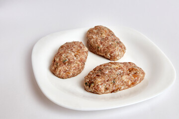 Raw cutlets from minced meat on a white plate.