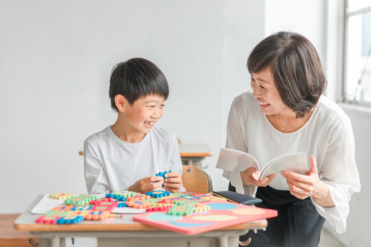 学校の教室で英語を勉強する男の子と女性講師（先生）
