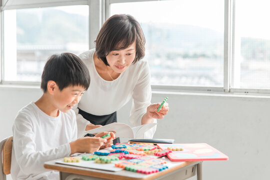 学校の教室で英語を勉強する男の子と女性講師（先生・教育）
