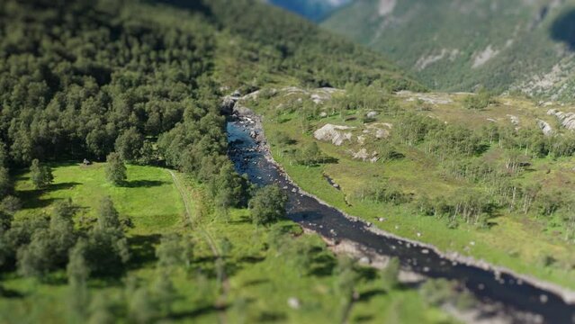 Aerial view of the river flowing through the wide rocky valley. Tilt-shift video.