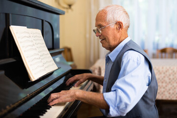 Elderly composer composes music and plays piano at home