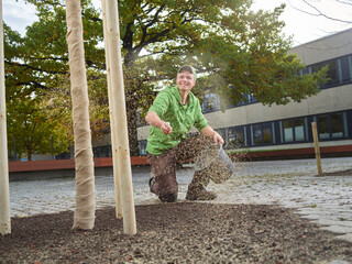 Happy young gardener scattering grass seeds