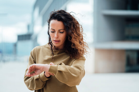 Businesswoman with curly hair checking time
