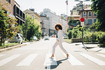 Young businesswoman crossing street on sunny day