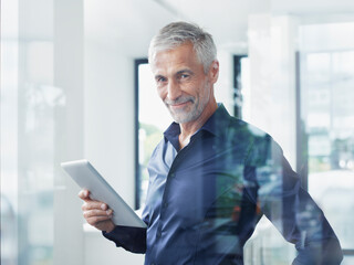 Smiling businessman with tablet PC standing in office