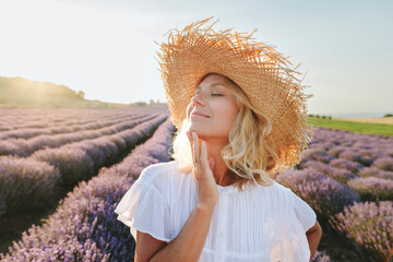 Smiling woman with eyes closed touching chin in lavender field