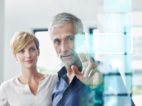 Mature businessman discussing over augmented bar graph on glass