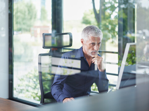Mature businessman working on desktop PC in office