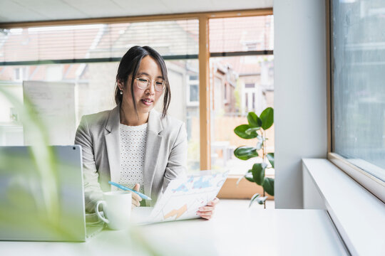 Businesswoman wearing eyeglasses reading document in office
