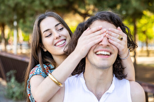 Happy young woman covering boyfriend's eyes at park