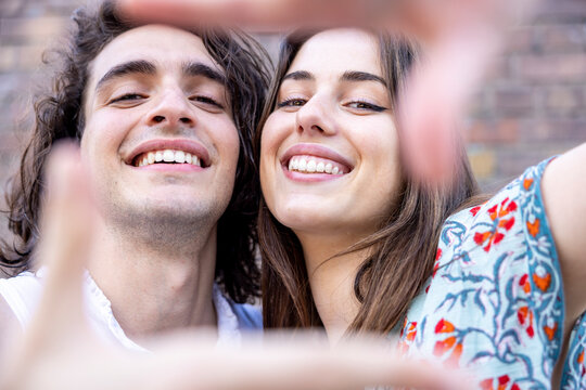 Happy young couple making finger frame with hands