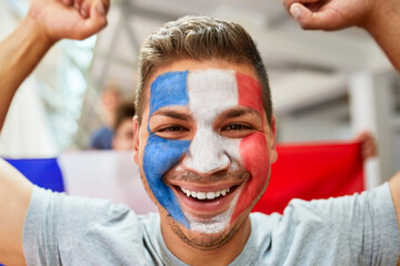Happy fan with French Flag painted on face at stadium