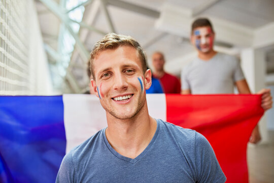 Smiling man with French Flag painted on face at sports event in stadium