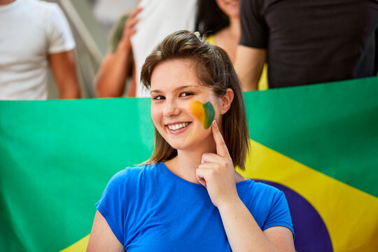 Smiling woman showing Brazil Flag painted on face