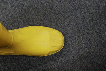 Yellow rubber boots that are waterproof are usually worn by construction workers, to protect their...