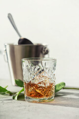 Glass of whiskey with ice cubes and ice bucket close up