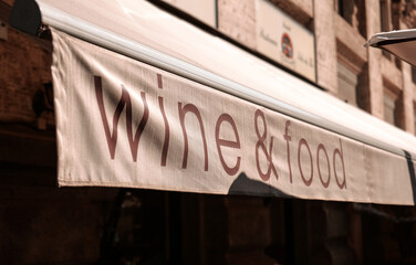 Wine and food concept text on the pergola roof of a restaurant terrace. Food and drinks industry.