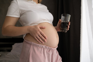 Close up of a pregnant belly and junk food.Cola and pregnancy. Pregnant female unhealthy motherhood