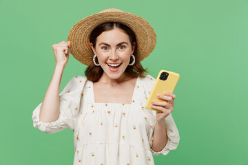 Young happy excited overjoyed woman she 20s wears white dress hat hold in hand use mobile cell...