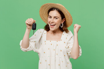 Young happy excited fun woman she 20s wears white dress hat hold car key fob keyless system do winner gesture isolated on plain pastel light green background studio portrait. People lifestyle concept.