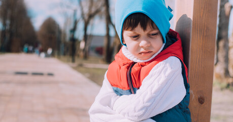 The offended boy is sitting on a lifestyle bench . Childish grievances. Childish anger. An article...