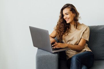 Attractive young woman using laptop while sitting on a couch at home