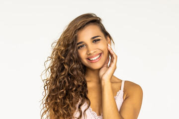Fototapeta premium Beauty portrait of young attractive woman with toothy smile. Long curly hair. Girl looking at camera. White background.