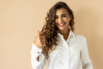 Young woman isolated en beige background smiling and raising thumb up