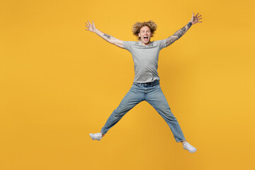 Fototapeta na wymiar Full body excited exultnt jubilant young caucasian man 20s he wear grey t-shirt look camera jump high with outstretched arms hands isolated on plain yellow backround studio. People lifestyle concept.