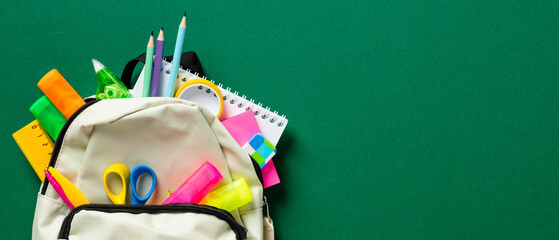 Back to school concept. Backpack with School supplies on green background. Wide banner template....