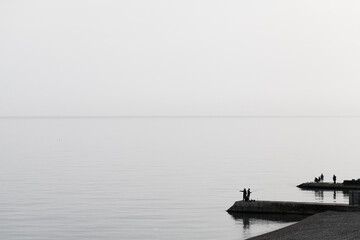 Silhouette photo of fishermen on a pier. Coastal view of Yalta