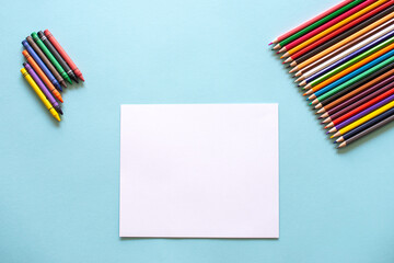 Fototapeta premium A set of bright stationery items on a blue background. Colour pencils