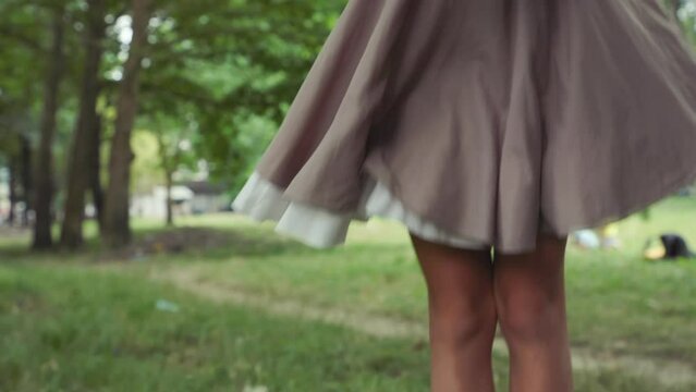 Children's education. Portrait of curious little girl in dress coming to pine cone, take it and looks it through a magnifying glass. Slow motion. Jib shot. The concept of scouting and childhood.