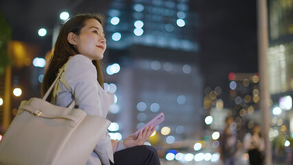 仕事終わりにスマホを見るビジネスウーマン